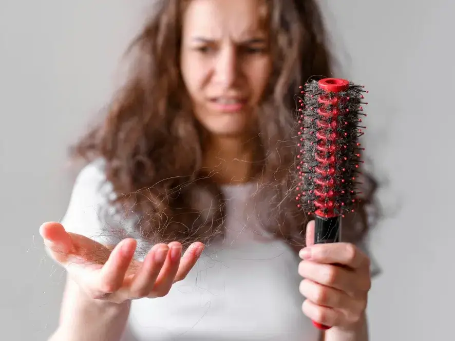 mulher jovem vendo que seu cabelo está caindo muito